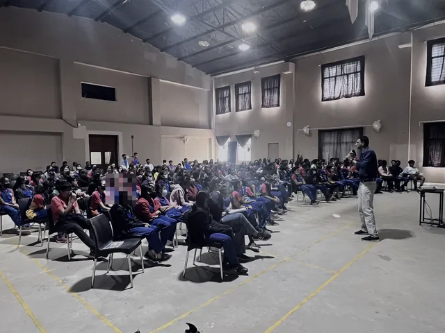 A speaker walking the aisle of a packed college hall